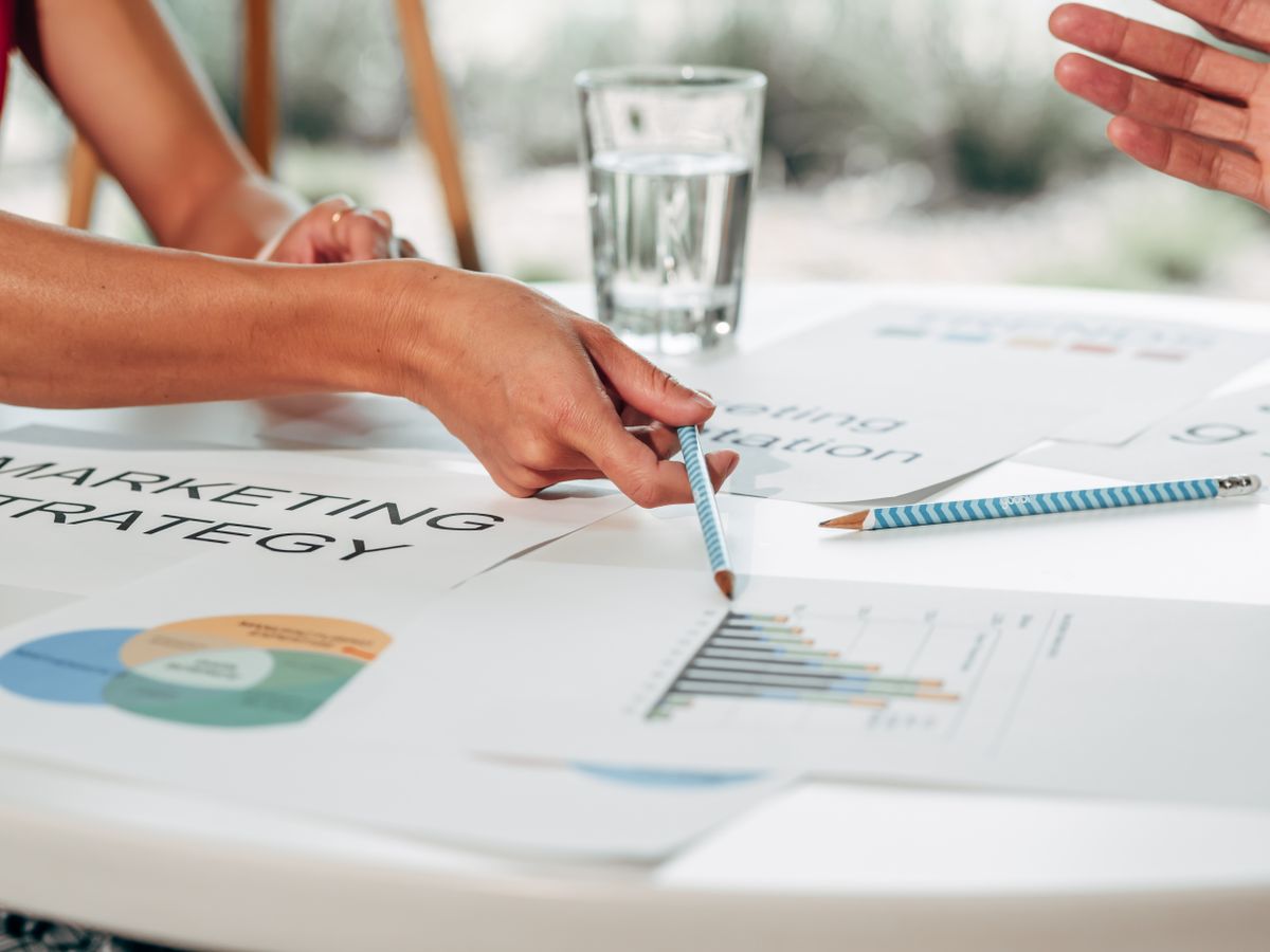 Equipo de marketing analizando estrategia de marca con documentos y gráficos en mesa de oficina