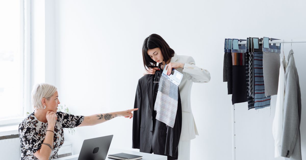 Dos mujeres colaborando en un proyecto de diseño y moda en una oficina moderna, representando colaboración de marca